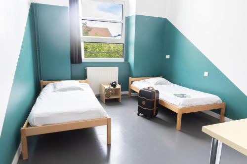 a room with two beds and a window at Auberge de Jeunesse HI Amiens in Amiens