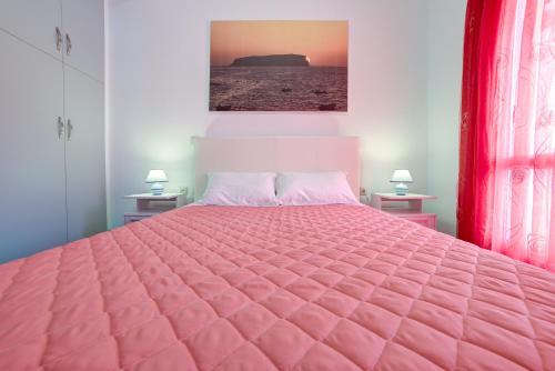 a pink bed with a pink comforter in a bedroom at Adelphi Apartments in Perissa