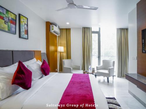 um quarto de hotel com uma grande cama branca com almofadas vermelhas em Saltstayz Grand - Unitech Cyber Park em Gurgaon