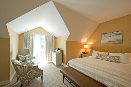 a bedroom with a bed and a chair and a window at The Grand Hotel in Kennebunk