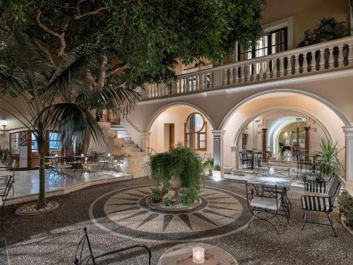 un vestíbulo con una palmera, mesas y sillas en Casa Delfino Hotel & Spa, en La Canea