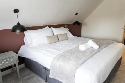um quarto com uma cama grande com lençóis brancos e almofadas em Elms Cottage em Spalding