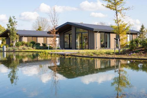 a house with a pond in front of it at Vakantiepark Molenvelden in Veldhoven