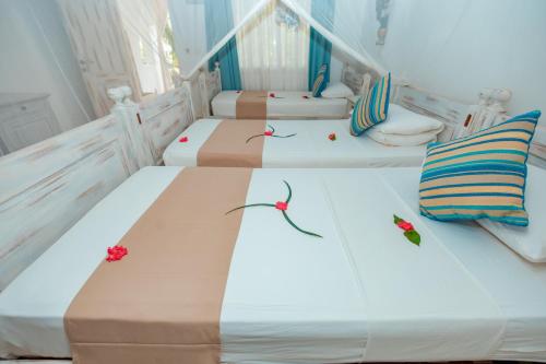 three beds in a room with flowers on them at Twiga Beach Resort in Watamu