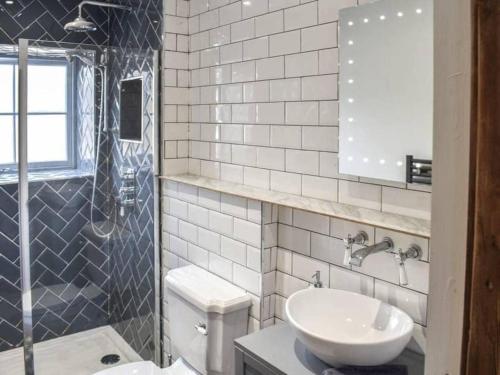 a bathroom with a sink and a toilet and a shower at Cosy 2 bedroom Cottage in a World Heritage Village in Shipley