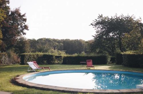 2 sillas y una piscina en un patio en La villa des Crénées, en Héron