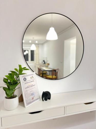 a mirror on top of a white dresser with a plant at Atmosfera Sibiu in Sibiu