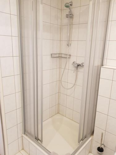 ショルテンスにあるHotel Mühleneckの白いタイル張りのバスルーム(シャワー付)