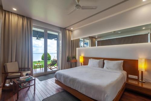 1 dormitorio con 1 cama grande y balcón en StayVista at The Rain - River Villa with Infinity Pool, en Alleppey