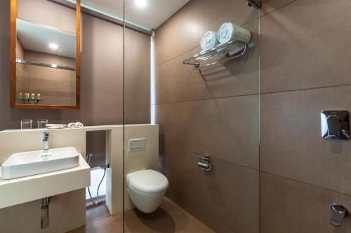 bagno con servizi igienici, lavandino e specchio di StayVista at The Rain - River Villa with Infinity Pool a Alleppey