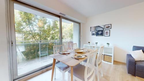 une salle à manger avec une table et des chaises et une grande fenêtre dans l'établissement Appartement La Fecht + parking, à Colmar