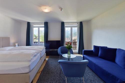 a bedroom with a bed and a blue couch at Hotel Sternen in Lenk