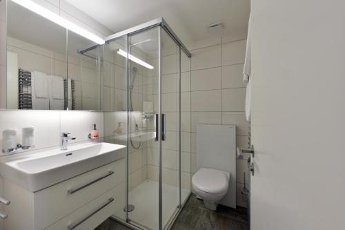 a white bathroom with a sink and a toilet at Hotel Sternen in Lenk