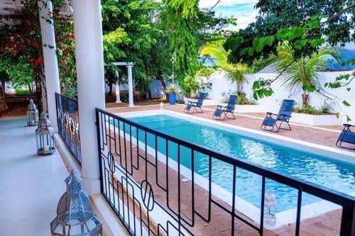 a swimming pool with chairs and a fence at The Kilimanjaro Villa in Moshi