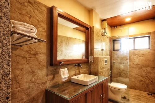 een badkamer met een wastafel, een toilet en een spiegel bij StayVista's Eden Bloom - Pet-Friendly Villa with Pool, Terrace & Lawn with Gazebo in Jabalpur