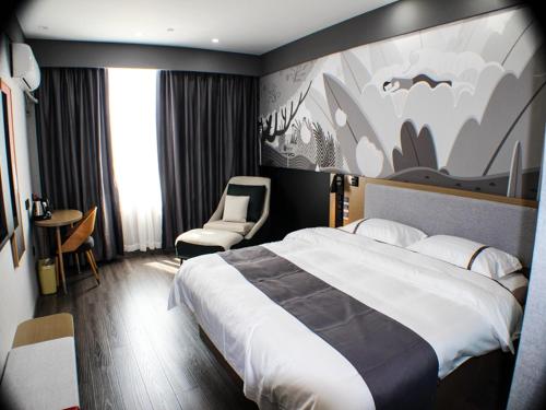 une chambre d'hôtel avec un grand lit et des chaises dans l'établissement Thank Inn Plus Chuzhou Mingguang Starlight Trade City, à Mingguang