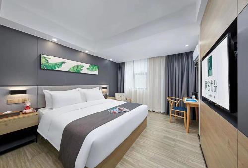 um quarto de hotel com uma cama grande e uma televisão em Thank Inn Plus Dongguan Dalingshan em Dongguan