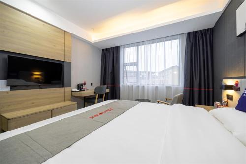 um quarto de hotel com uma cama grande e uma secretária em Junyi Hotel Yongzhou Dao County Middle Xiaoshui Road 