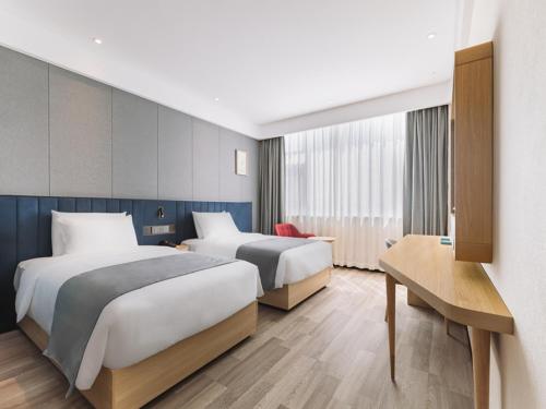 ein Hotelzimmer mit 2 Betten und einem Tisch in der Unterkunft LanOu Hotel Qingdao West Station Haixi Road in Qingdao
