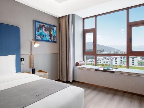 LanOu Hotel Lhasa Municipal Government Tibet University في لاسا: غرفة فندقية بسرير ونافذة كبيرة