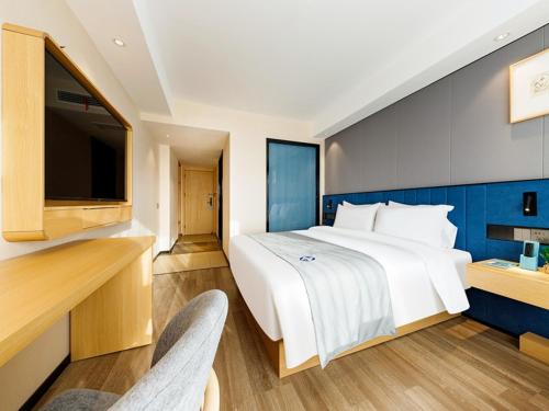 a bedroom with a large bed and a tv at LanOu Hotel Xuchang Caowei Ancient City in Xuchang