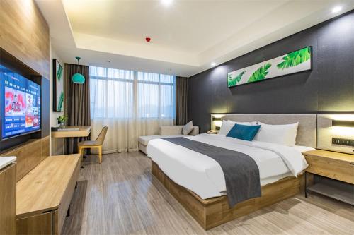 a hotel room with a large bed and a flat screen tv at Thank Inn Plus Shaoguan Qujiang District Maba in Shaoguan