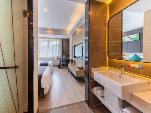 a hotel room with a sink and a bedroom at Thank Inn Plus Shijiazhuang Xinhua District West Beierhuan Road in Shijiazhuang