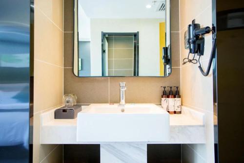 La salle de bains est pourvue d'un lavabo blanc et d'un miroir. dans l'établissement Thank Inn Plus Xing'an Senfa Four Season Flower City, à Ulanhot