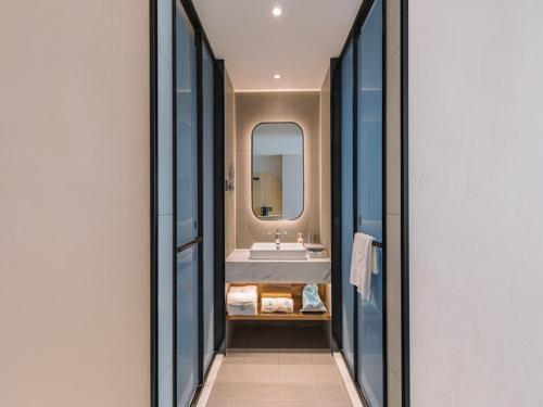 ein Bad mit einem Waschbecken und einem Spiegel in der Unterkunft LanOu Hotel Qingdao West Station Haixi Road in Qingdao