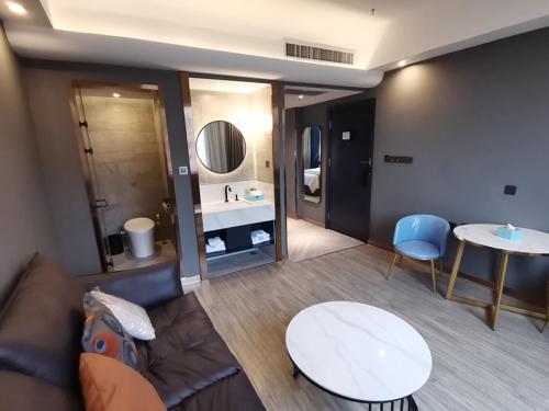 een woonkamer met een bank, een tafel en een wastafel bij Thank Inn Plus Hanzhong High-Speed Railway Station in Hanzhong