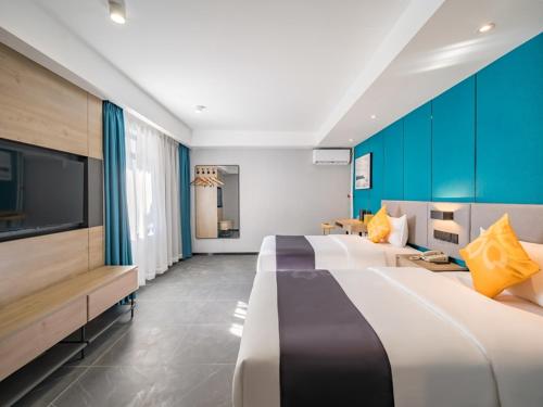 a hotel room with two beds and a flat screen tv at Feronia Hotel Beijing Bird's Nest Datun Road in Beijing