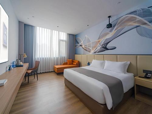 een hotelkamer met een groot bed en een bureau bij LanOu Hotel Qianjiang High-Speed Railway Station Lobster City in Qianjiang