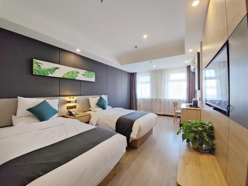 a hotel room with two beds and a television at Thank Inn Plus Lanzhou Dongfanghong Plaza Pingliang Road in Lanzhou