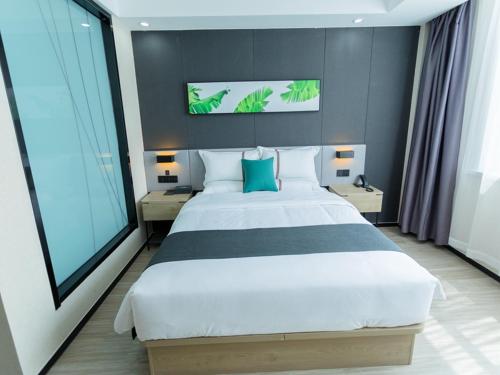a bedroom with a large white bed with blue pillows at Thank Inn Plus Xing'an Senfa Four Season Flower City in Ulanhot