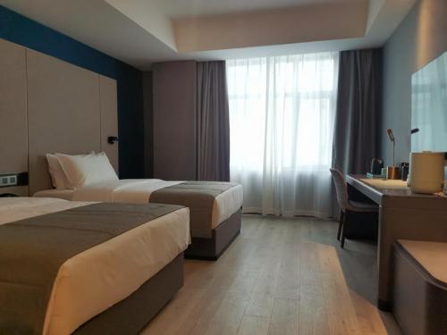 um quarto de hotel com duas camas e uma secretária em LanOu Hotel Longjiang Road Shigatse em Shigatse