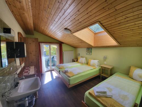 a bedroom with two beds and a sink and a skylight at Pension Heino in Saas-Grund