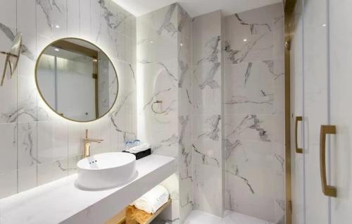 a white bathroom with a sink and a mirror at LanOu Hotel Chongqing Hongou Square Wanzhou Guanyinyan in Wanzhou