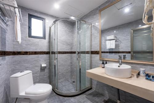 a bathroom with a shower and a toilet and a sink at Junyi Hotel Wuhan Liuduqiao Subway Station in Wuhan