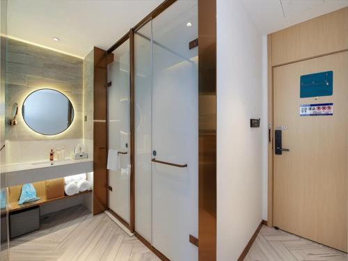 La salle de bains est pourvue d'une douche, d'un lavabo et d'un miroir. dans l'établissement LanOu Hotel Taikoo Li Night Market Kuqa City, à Kuqa