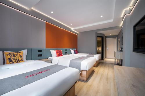 a row of beds in a hotel room at Junyi Hotel Wuhan Liuduqiao Subway Station in Wuhan