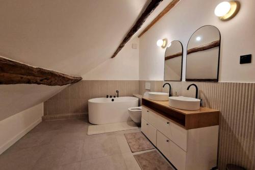 łazienka z 2 umywalkami i wanną w obiekcie Les Jardins de Rosie 