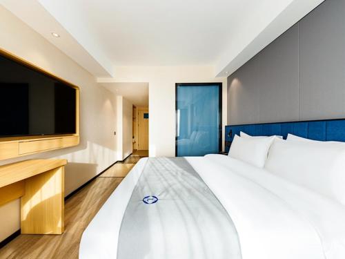 a bedroom with a large white bed and a flat screen tv at LanOu Hotel Xuchang Caowei Ancient City in Xuchang