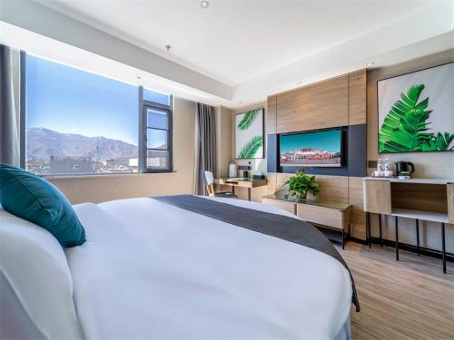 um quarto com uma grande cama branca e uma grande janela em Thank Inn Plus Tibet Lhasa East Dangre Road em Lassa