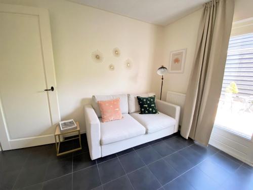 a living room with a white couch and a window at DJP76 mooi gelijkvloers appartement met terras in Domburg