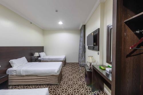 a hotel room with two beds and a flat screen tv at Abdul Hafez Al Humaidan Hotel in Makkah