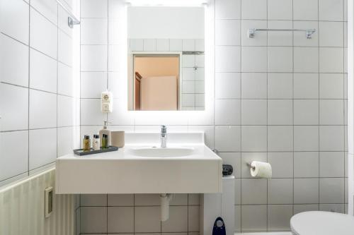 a white bathroom with a sink and a mirror at Hotel-Zimmer direkt am See in Gmunden