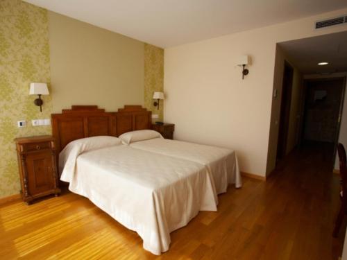 a bedroom with a large white bed and a wooden floor at Hotel Vila do Val in Ferreira