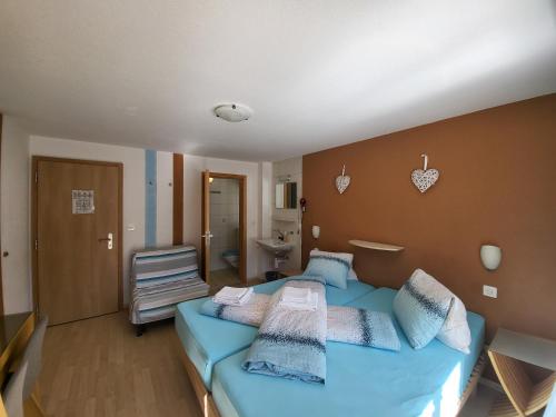 a bedroom with a blue bed and a bathroom at Pension Heino in Saas-Grund