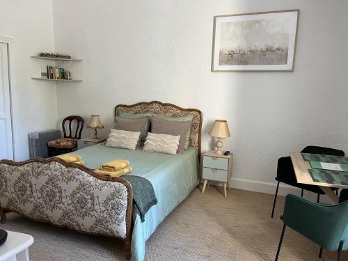 um quarto com uma cama, uma mesa e uma cadeira em Au Petit Faubourg em Grignan