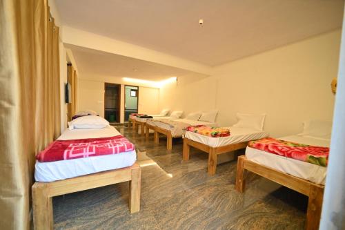 a group of four beds in a room at Coorg HomeStay Resort in Kushālnagar